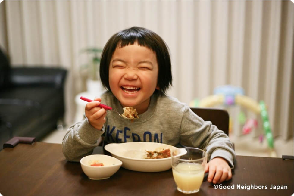 笑顔で食事を楽しむ子ども。ひとり親家庭へのフードバンク支援を通じた取り組みの様子。